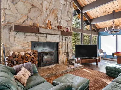 a living room with a stone fireplace and a television at Awesome Home Above the Lake - Dogs Welcome VH315 in Bear Valley