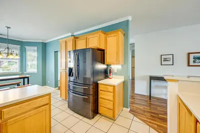 a kitchen with a stainless steel refrigerator and wooden cabinets at 26 Mi to Fresno Pet-Friendly Home in Reedley! in Reedley