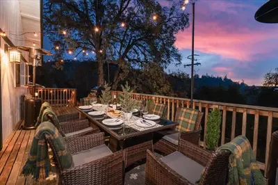 a patio with a table and chairs on a deck at Sequoia's Dream with Mountain View, Spa, Heated Floor, Bar, Cinema! in Oakhurst