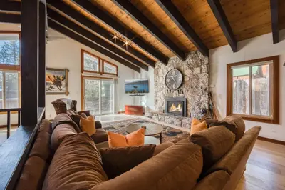 a living room with a large couch and a stone wall at Wanderlust Retreat by Tahoe Getaways - 4BR Pet-Friendly w Fenced Yard, Walking Distance to Lake! in Tahoe City