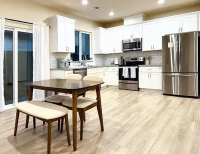 a kitchen with white cabinets and a table and chairs at 5 Min Walk to UCD Med Ctr - Stylish New Build Home in Sacramento