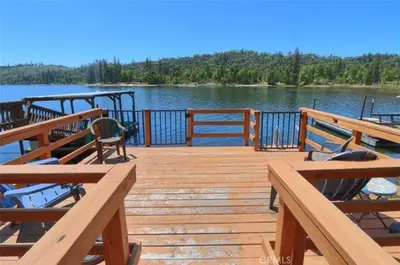 a wooden deck with tables and chairs on a lake at Lake View Cabin Private Dock Free Night Special in Bass Lake