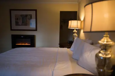 a bedroom with a white bed and a fireplace at Tea Garden Lodge in South Lake Tahoe