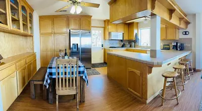a kitchen with a table and a refrigerator at Shaver Lake, 4 BDR HOT TUB Misty Mountain Retreat in Shaver Lake