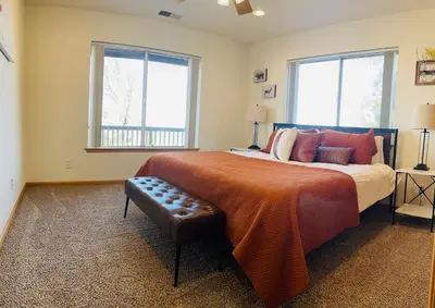 a bedroom with a large bed and two windows at Shaver Lake, 4 BDR HOT TUB Misty Mountain Retreat in Shaver Lake