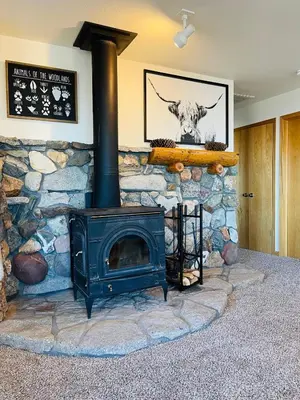 a stone fireplace with a stove in a room at Shaver Lake, 4 BDR HOT TUB Misty Mountain Retreat in Shaver Lake