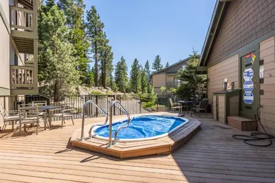 a hot tub on a deck next to a building at Crestview #3 bldg C 1 Bedroom plus Den / 2 Bathroom, close to town shuttle and short walk to village in Mammoth Lakes