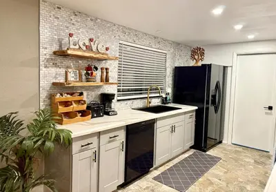 a kitchen with white cabinets and a black refrigerator at The Ultimate Mountain Retreat close Yosemite and Bass Lake in Oakhurst