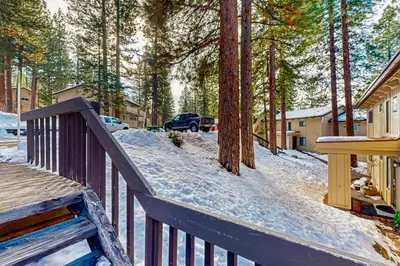 a wooden deck with snow on it next to trees at The Pines Chalet in Incline Village
