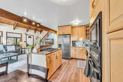 a kitchen with wooden cabinets and appliances and a living room at Cozy Kings Beach Vacation Rental with Deck in Kings Beach