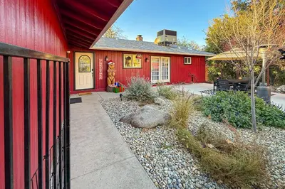 a red house with a fence in front of it at The Firelight Lodge in Oakhurst