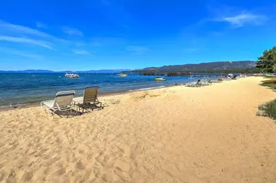two chairs sitting on a beach near the water at Lakeland Village 2 Bed Condo Pool View in South Lake Tahoe