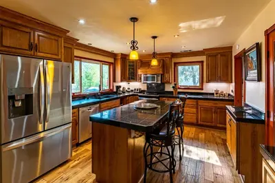 a kitchen with wooden cabinets and a stainless steel refrigerator at Waterfall Lodge near Yosemite Endless Pool, Hot Tub, Playground in Oakhurst