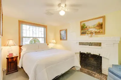 a bedroom with a white bed and a fireplace at Steps to Truckee River Walk Rose Cottage in Reno