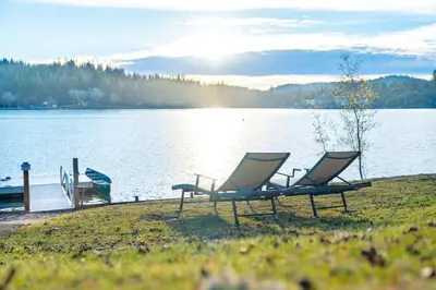 two chairs sitting on the shore of a lake at Lakefront Villa with 180 degree view private dock and boats in Groveland