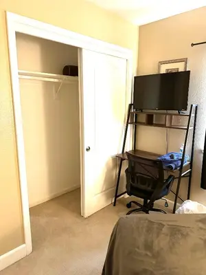 a bedroom with a desk with a television and a door at serenity in Fresno