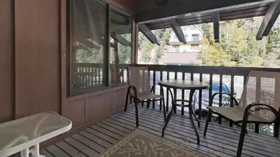 a porch with a table and chairs on a balcony at Ski Den - Steps to Mammoth Village! in Mammoth Lakes