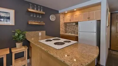 a kitchen with a stove and a white refrigerator at Ski Den - Steps to Mammoth Village! in Mammoth Lakes