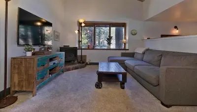 a living room with a couch and a tv at Ski Den - Steps to Mammoth Village! in Mammoth Lakes