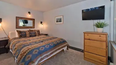 a bedroom with a bed and a dresser and a television at Ski Den - Steps to Mammoth Village! in Mammoth Lakes