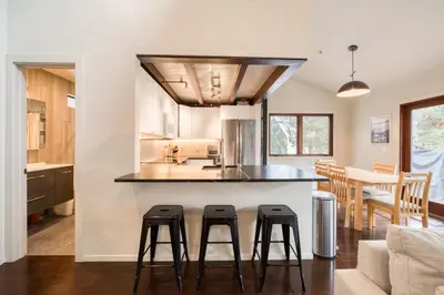 a kitchen with three bar stools in front of a counter at Valley View Townhome # 10 at Palisades by Tahoe Getaways - Shuttle & Walk to the Village! in Olympic Valley