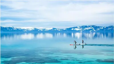 two people are standing on a paddle board in the water at 6000 sqft Pine House with indoor swimming pool in Reno