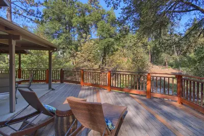 a deck with two chairs and a table on it at Tranquility House-Riverfront-Fireplace-Sleeps six in Oakhurst
