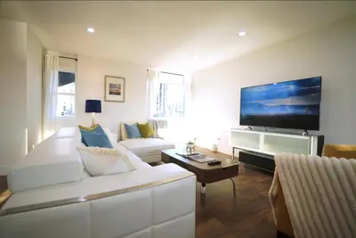 a living room with a white couch and a flat screen tv at Stunning Waterfront 3BR Retreat - Perfect Getaway in Discovery Bay