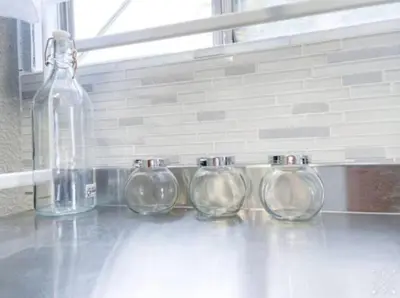 a group of four glass jars sitting next to a bottle at Nifty Trailer With Spacious Parking in Visalia