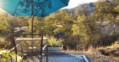 a patio with a chair and an umbrella at Cozy Farm Stay for Two in Three Rivers
