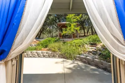 a view of a garden through the curtains of a window at Cody's Comfy Cabin- Near Yosemite in Mariposa