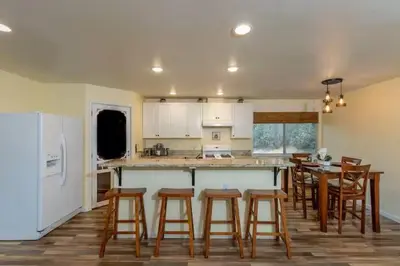 a kitchen with wooden stools and a kitchen with a table at Cody's Cozy Cottage-Near Yosemite in Mariposa