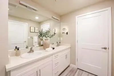 a white bathroom with a sink and a mirror at Amazing Water View with Jacuzzi & Sky Lounge in Sparks