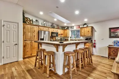 a kitchen with wooden cabinets and a large island with bar stools at Kamp Koyukon 1939K in South Lake Tahoe