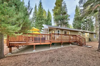 a house with a large deck in the woods at 1540TS Snowy Owl Cabin in South Lake Tahoe