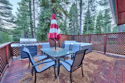 a patio with a table with an umbrella and a grill at 1965NP The Bears Den in South Lake Tahoe