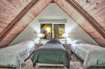 a attic bedroom with three beds and a window at Cholula Chalet 811C in South Lake Tahoe