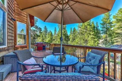 a table and chairs on a deck with an umbrella at Das Waldhaus 1973P in South Lake Tahoe