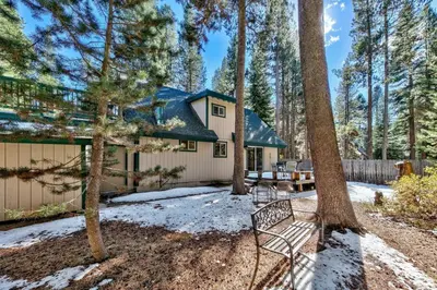 a house in the woods with a bench in the yard at 1207S Cabin in the Pines in South Lake Tahoe