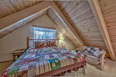 a attic bedroom with a bed and a chair at 1625A Atroari Chalet in South Lake Tahoe