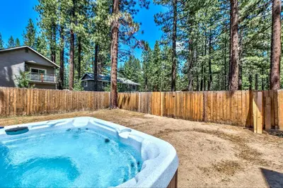 a hot tub in a yard next to a wooden fence at 1213GB Golden Bear Tahoe Home in South Lake Tahoe