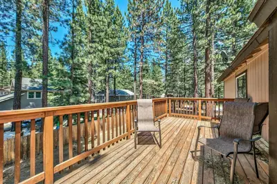 a wooden deck with two chairs and trees at 1213GB Golden Bear Tahoe Home in South Lake Tahoe