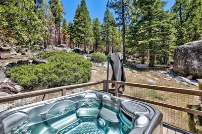 a bath tub on a deck with a view of a forest at 3001R Reindeer A Frame Cabin in South Lake Tahoe