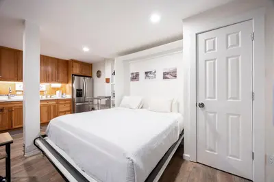 a bedroom with a white bed and a kitchen at Stunning Deluxe King Studio #124 at Donner Lake Village in Truckee
