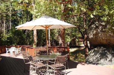 a table and chairs under an umbrella on a deck at 68 Wawona Dome View in North Wawona