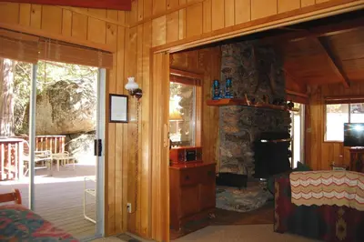 a living room with a stone fireplace and a bedroom at 68 Wawona Dome View in North Wawona