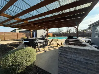 a patio with a grill and a table and chairs at GUEST RANCH HOUSE w POOL access near NATL PARKS in Dinuba
