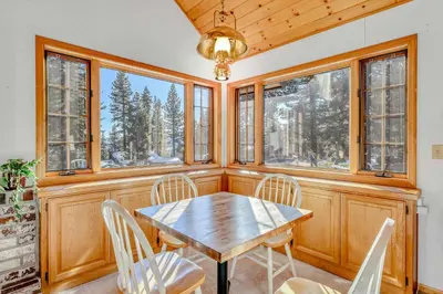 a dining room with a table and chairs and windows at Spacious Tahoe City Home with Foosball and Lake Views in Tahoe City