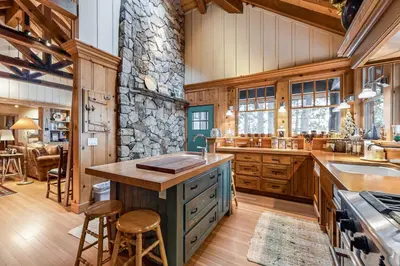 a kitchen with wooden cabinets and a stone wall at Lakefront Luxury in Tahoe City