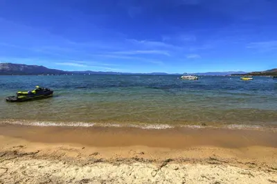 a boat in the water near a beach at Lakeland Studio - Walk to Casinos, Restaurants And Gondola in South Lake Tahoe